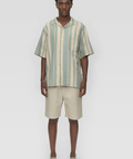 Man wearing a striped shirt and beige shorts on a white background