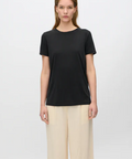 Woman wearing a black t-shirt and beige pants on a white background