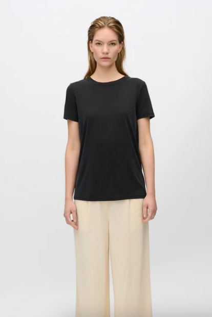 Woman wearing a black t-shirt and beige pants on a white background