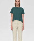 Person wearing a green t-shirt and beige pants on a white background