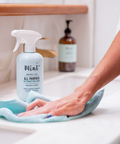Person cleaning a surface with a bottle of Mint all-purpose cleaner and a cloth.