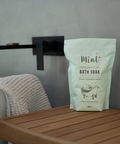 Bag of Mint Bath Soak on a wooden surface with a towel in the background