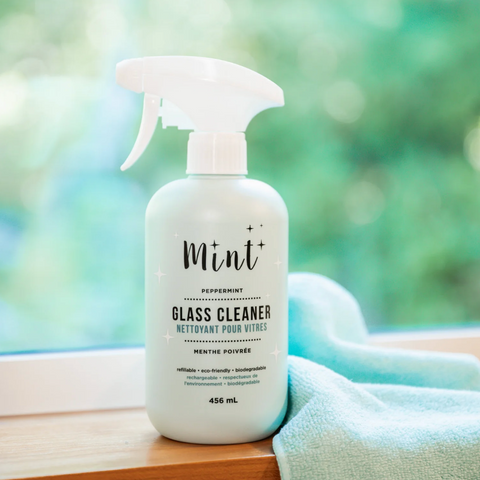 Glass cleaner bottle with 'Mint' branding on a blurred natural background