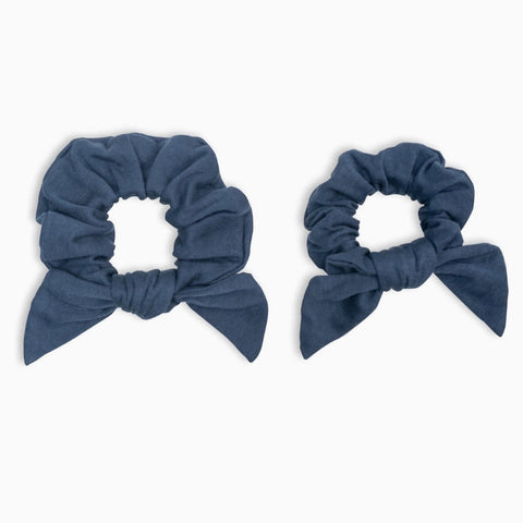 Two blue scrunchies with bow designs on a white background
