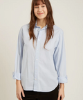 Woman wearing a light blue button-up shirt against a plain background