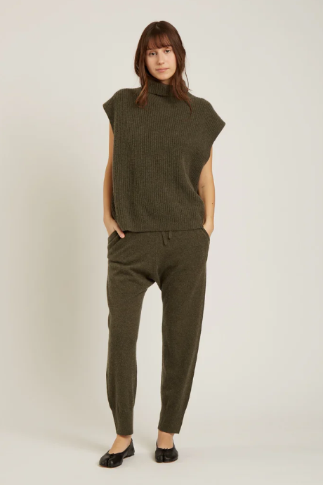 Woman wearing a green sleeveless knit top and pants on a white background