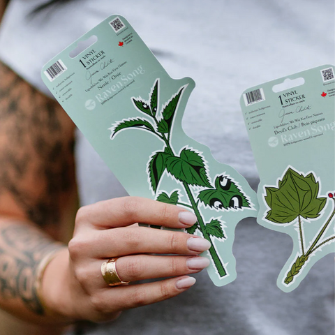 Person holding two plant-themed stickers with a gray shirt background