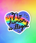 Heart-shaped sticker with 'No human is illegal' text on a rainbow gradient background