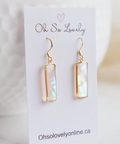 A pair of gold-tone rectangular drop earrings with iridescent white pearly inlay, displayed on a white card that reads 'Oh So Lovely' and 'Ohsolovelyonline.ca'.