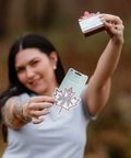 Person holding a soap bar and packaging with a maple leaf design outdoors