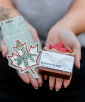 Person holding a bar of soap labeled 'Raven Song' and a branded leaf-shaped product.