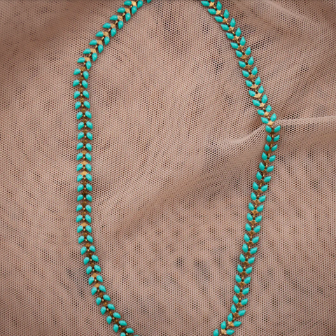 Turquoise beaded necklace on a beige fabric background