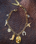 Gold bracelet with various charms on a brown leather background