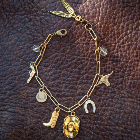 Gold bracelet with various charms on a brown leather background