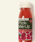 Bottle of Organic Pick-Me-Up with red liquid and white cap on a light beige background