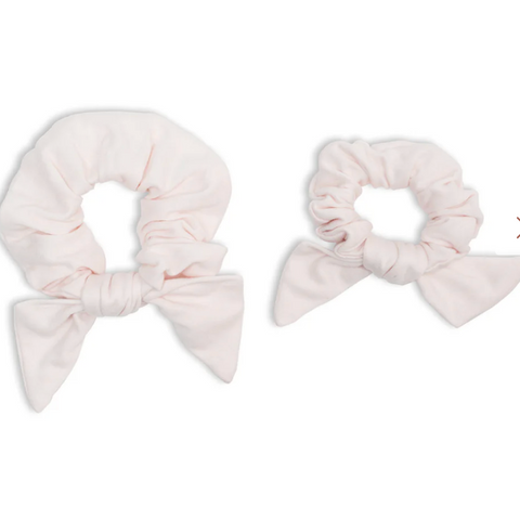 Two light pink scrunchies with bow details on a white background