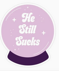 Purple crystal ball with 'He Still Sucks' text on a white background