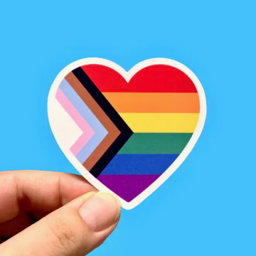 Heart-shaped sticker with rainbow and plus symbol held by a hand against a blue background