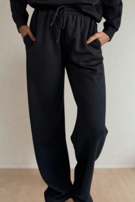 Person wearing black pants against a plain background
