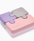 Melii puzzle-style storage containers with interlocking lid pieces in pastel purple, pink, and gray, shown on a clean white background.