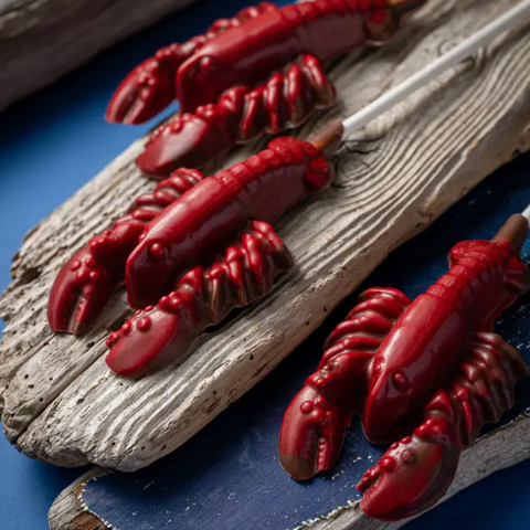 Red lobster-shaped candies on a wooden surface with a blue background