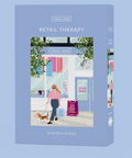 A 1000-piece jigsaw puzzle box titled 'RETAIL THERAPY' by Classy Cards, featuring a light blue packaging design with an illustration of a woman walking a dog outside a clothing store.