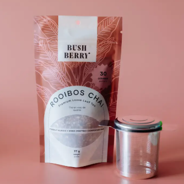 Bush Berry Rooibos Chai packaging with a clear container on a pink background