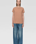 Woman wearing a brown t-shirt and blue jeans on a white background