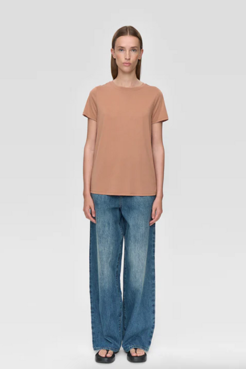 Woman wearing a brown t-shirt and blue jeans on a white background