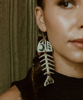 Closeup of model wearing the ivory acrylic Medium Salmon Ghost earring from Copper Canoe Woman.