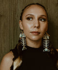 A model wearing the Medium Salmon Ghost earring from Copper Canoe Woman in ivory acrylic.