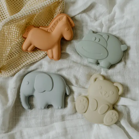 Four silicone animal-shaped teether toys on a white fabric background