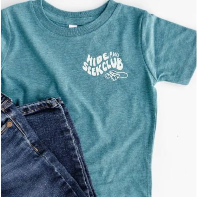 Blue t-shirt with 'Hide and Seek Club' text and jeans on a white background