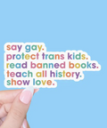 Colorful text sticker with social justice message held by a hand against a blue background