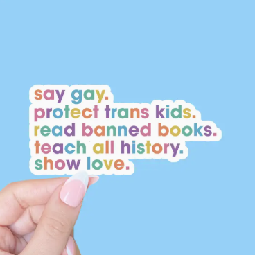 Colorful text sticker with social justice message held by a hand against a blue background