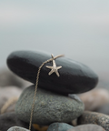 Starfish pendant necklace on a stone with a blurred natural background