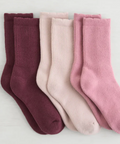 Set of three pairs of socks in maroon, pink, and light pink on a white background.