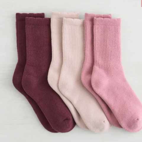 Set of three pairs of socks in maroon, pink, and light pink on a white background.