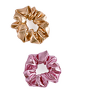 Two metallic scrunchies on a plain white background, one in champagne gold and one in metallic pink.