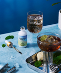 Shroom Soda bottle with cocktails and bar tools on a blue surface