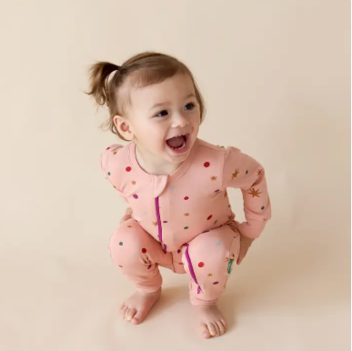 Baby wearing a pink outfit with red polka dots on a beige background