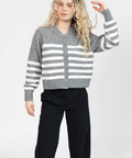 Person wearing a gray and white striped sweater with black pants on a white background