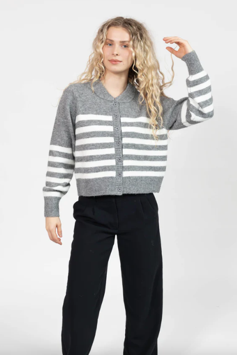 Person wearing a gray and white striped sweater with black pants on a white background