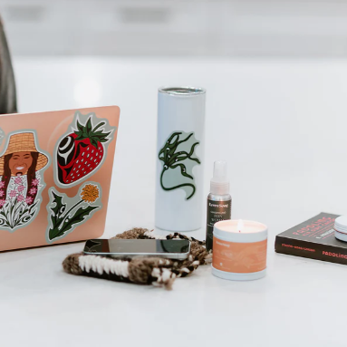 Laptop with stickers on a desk next to a phone, water bottle, and other items