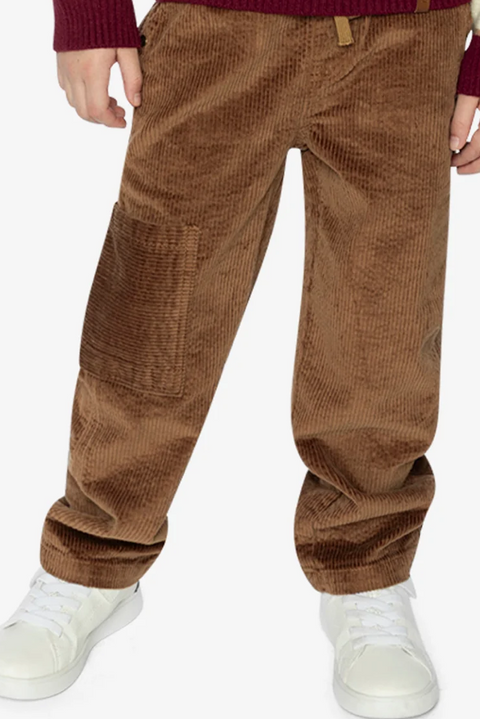 A close-up of a child wearing brown corduroy pants, a burgundy sweater, and white sneakers against a plain white background.