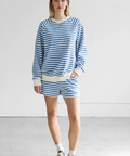 Woman wearing a blue and white striped outfit standing against a white background
