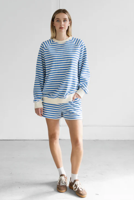 Woman wearing a blue and white striped outfit standing against a white background