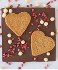 Chocolate bar with heart-shaped cookies and decorative elements on a white background