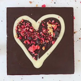 Chocolate dessert with a heart-shaped topping on a white surface