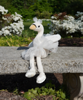 White plush duck toy sitting on a stone bench with a garden background